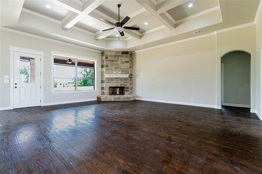 Unfurnished living room featuring a fireplace, coffered ceiling, ceiling fan, and dark wood-type flooring