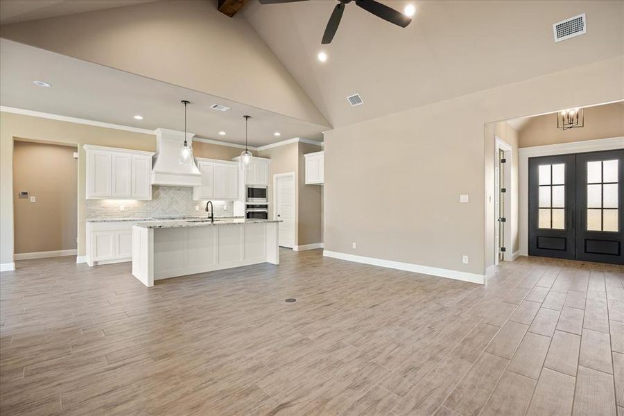 Unfurnished living room with light hardwood / wood-style flooring, high vaulted ceiling, and crown molding