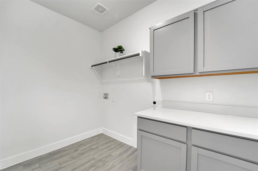 Washroom with washer hookup, hookup for an electric dryer, light hardwood / wood-style floors, and cabinets