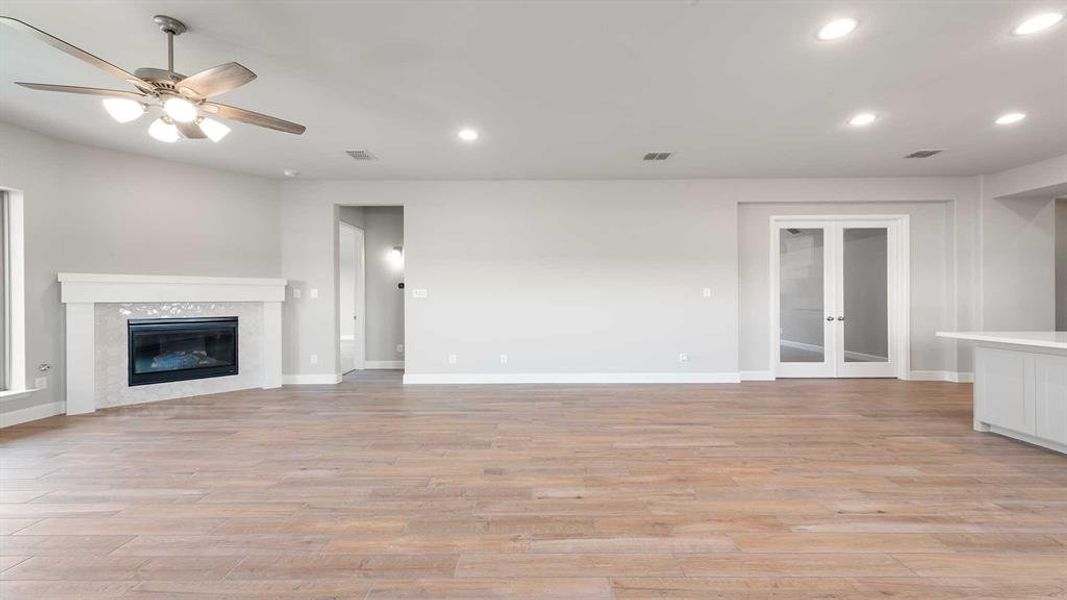 Unfurnished living room featuring light hardwood / wood-style flooring, a high end fireplace, and ceiling fan