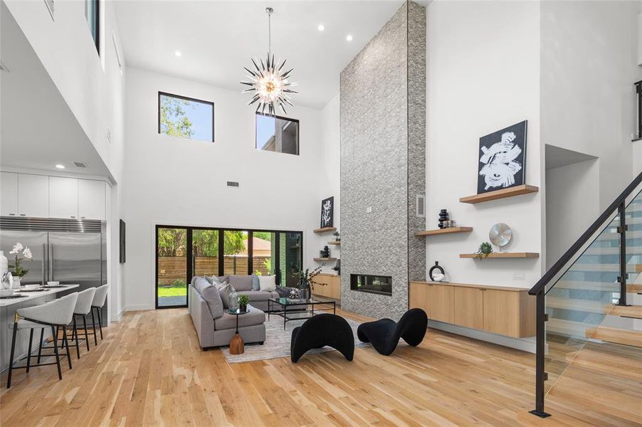 Living room with a fireplace, light wood-type flooring, and a high ceiling