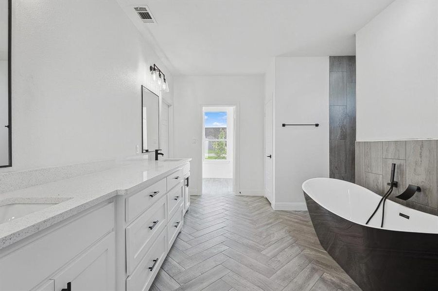 Bathroom with parquet flooring, a bathing tub, and vanity