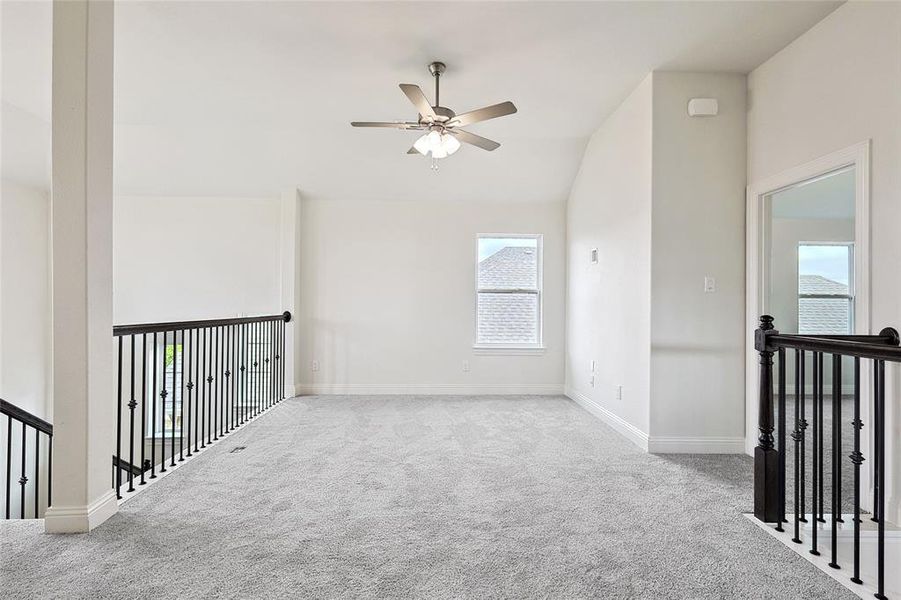 Spare room featuring a wealth of natural light, lofted ceiling, light carpet, and ceiling fan