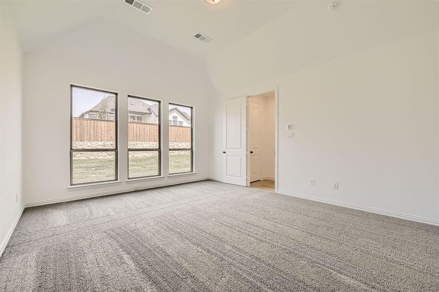 Unfurnished room with light colored carpet and high vaulted ceiling