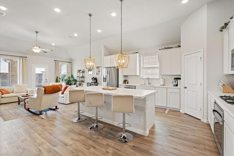 Oversized kitchen island with quartz counter tops, pendant lights, and custom white cabinets