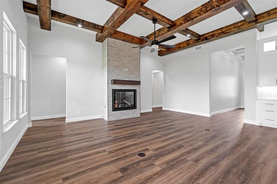 Unfurnished living room with dark hardwood / wood-style flooring, coffered ceiling, ceiling fan, and a fireplace