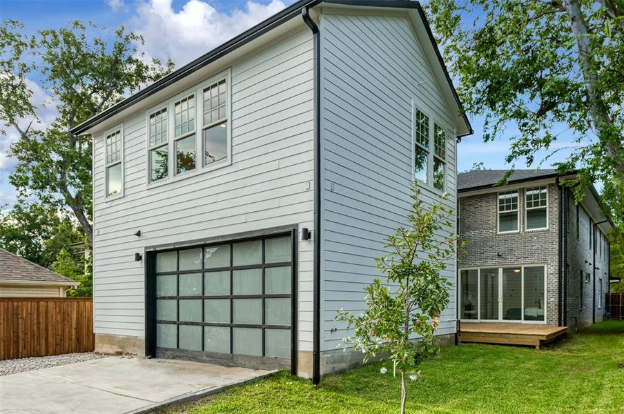 Rear view of property with a garage and a lawn