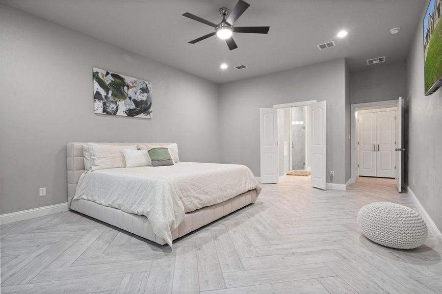 Bedroom with ceiling fan, connected bathroom, and light parquet flooring