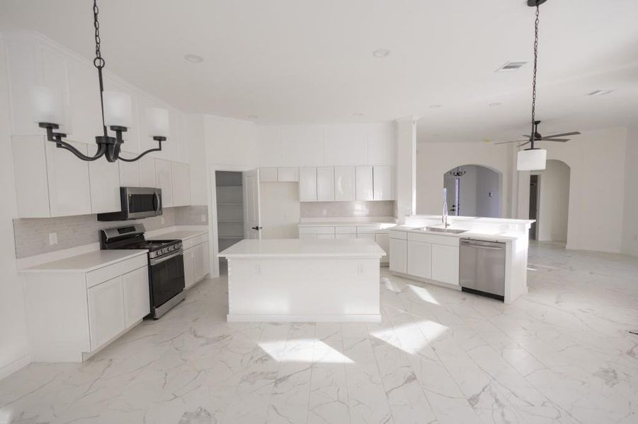 Kitchen featuring stainless steel appliances, white cabinets, a center island, and backsplash