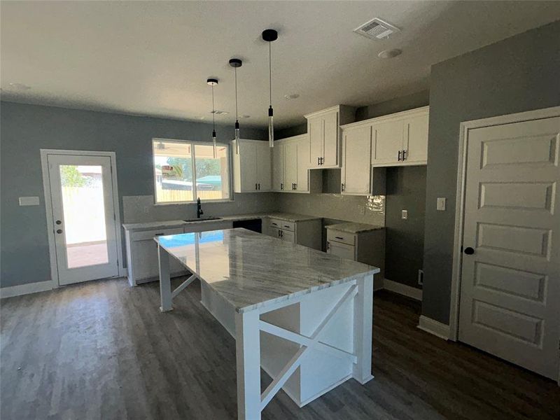 Kitchen with tasteful backsplash, white cabinets, sink, a kitchen island, and dark hardwood / wood-style flooring