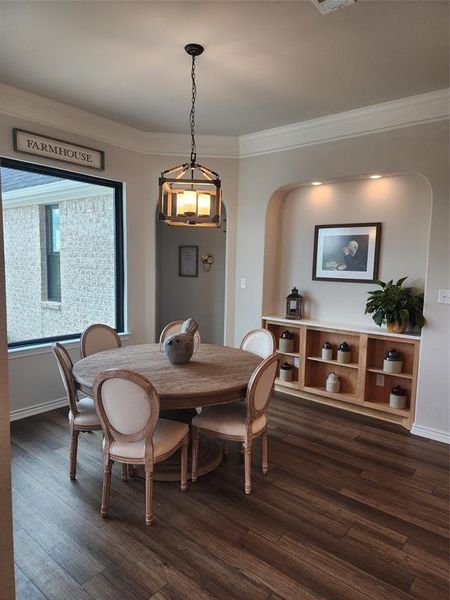 Dining room featuring crown molding, dark hardwood / wood-style floors, and a chandelier