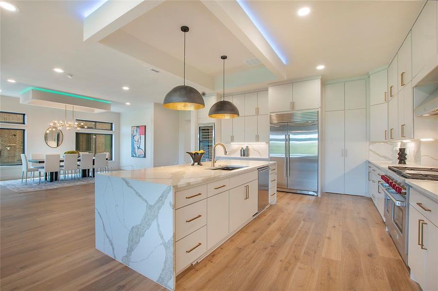 Kitchen with sink, pendant lighting, high quality appliances, and light wood-type flooring