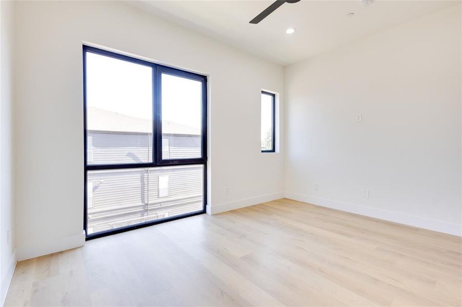 Empty room featuring ceiling fan, light hardwood / wood-style flooring, and a wealth of natural light