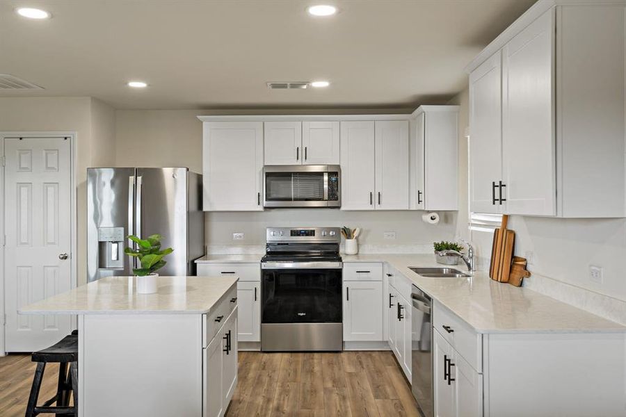 The gorgeous kitchen features quartz countertops and stainless steel alliances.