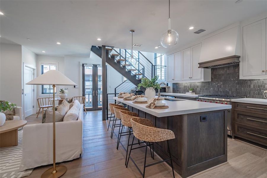 Kitchen featuring Wolf Range stove, quartz countertops, pendant lighting, and custom range hood