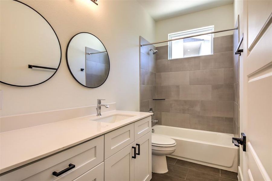 Second bathroom with ceramic tile flooring and tub-surround, storage drawers