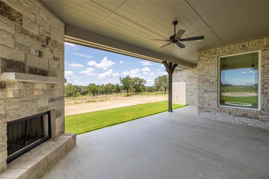 View of patio / terrace featuring an outdoor stone fireplace and ceiling fan