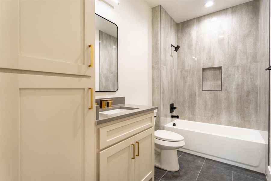 Full bathroom featuring vanity, tile patterned floors, toilet, and tiled shower / bath