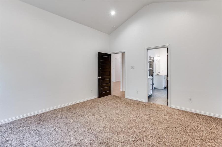 Unfurnished bedroom with light carpet and high vaulted ceiling