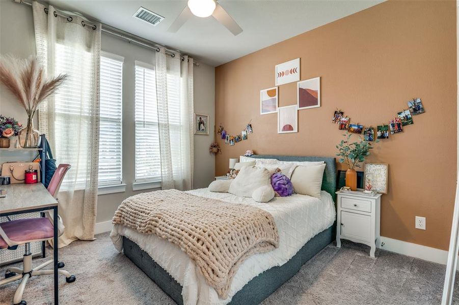 Bedroom featuring light carpet, multiple windows, and ceiling fan