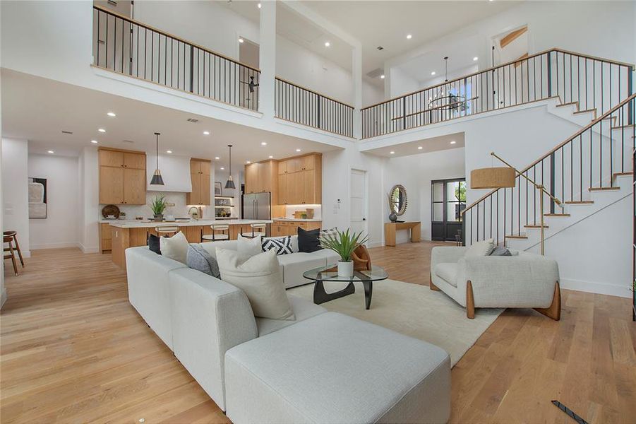 Living room with light hardwood / wood-style flooring, a high ceiling, and sink