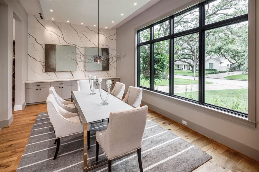 Formal dining covered with exquisite finishes, center tray ceiling, built-in serving buffet and through a wall of windows you can enjoy the serene views of the front yard