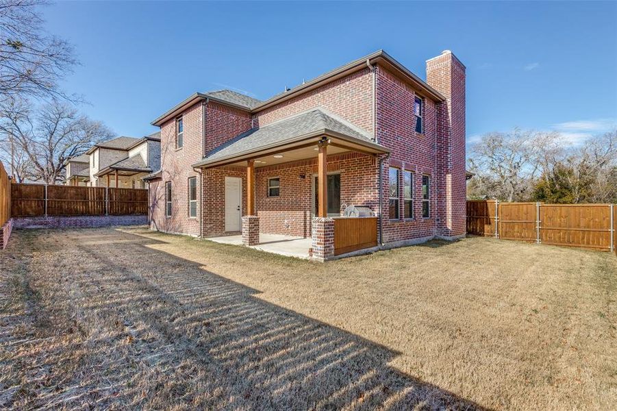 Back of house with a lawn and a patio