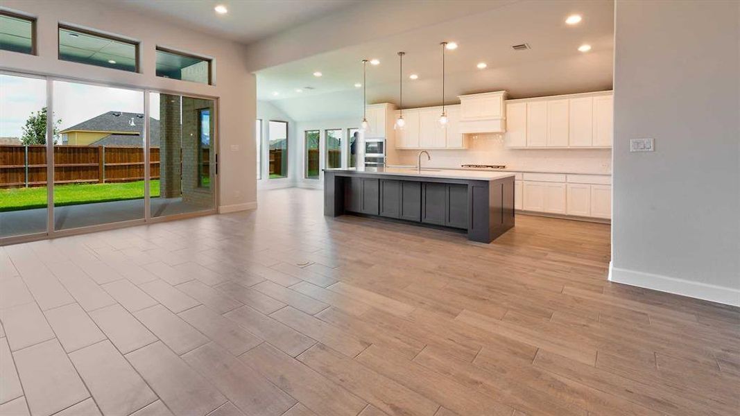 Kitchen featuring sink, white cabinets, pendant lighting, and a center island with sink