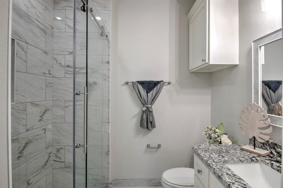 Bathroom featuring vanity, toilet, and a shower with shower door