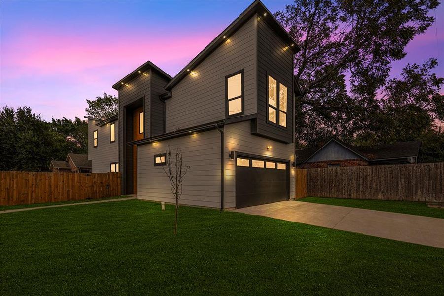 View of front of property with a garage and a lawn