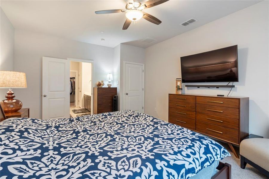 Carpeted bedroom featuring ensuite bath and ceiling fan