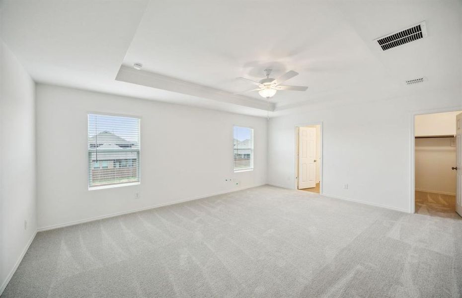 Owner's suite with large windows and tray ceiling  *real home pictured