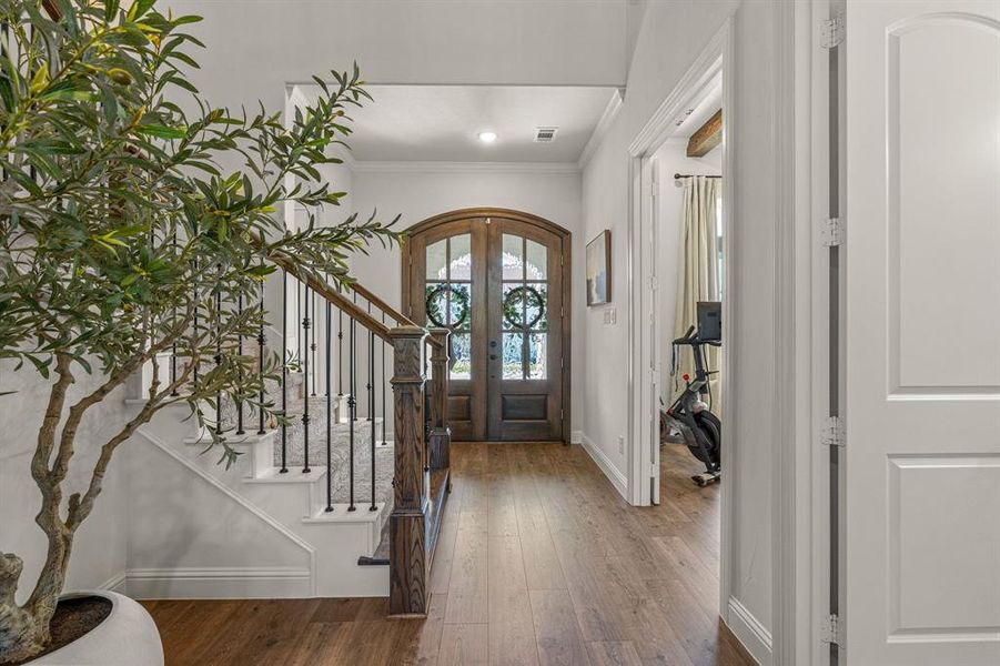 Foyer entrance featuring dark wood-type flooring, crown molding, and french doors