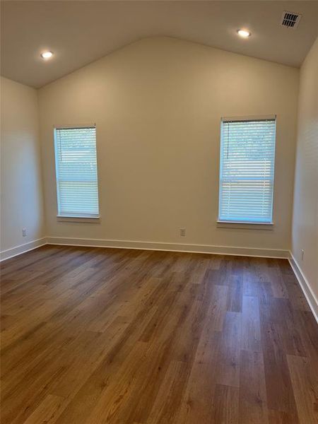 Empty room featuring plenty of natural light, dark wood-type flooring, and vaulted ceiling