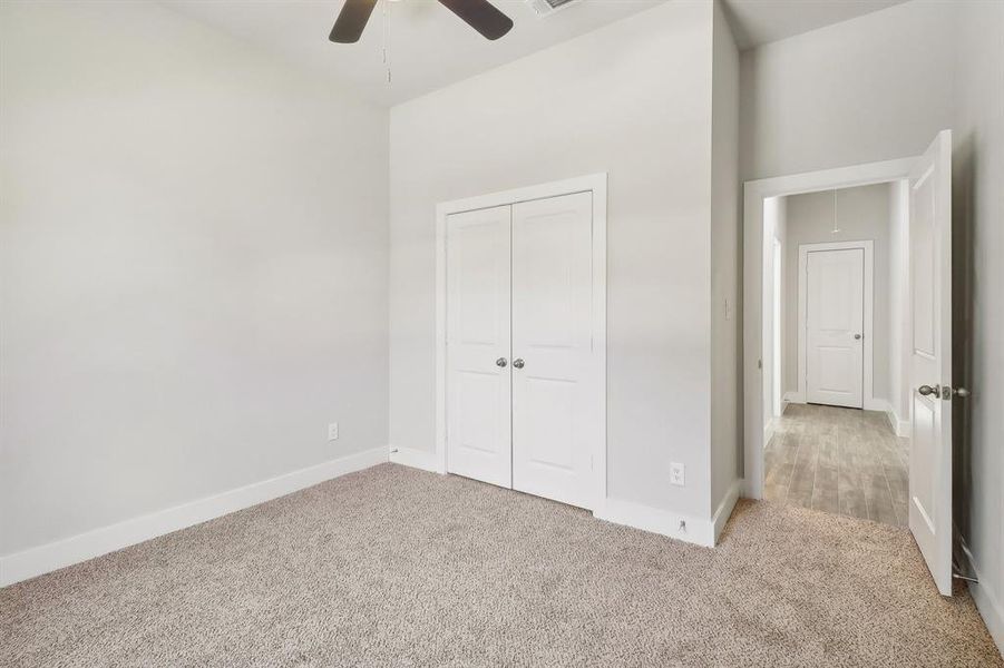 Unfurnished bedroom featuring ceiling fan, light colored carpet, and a closet