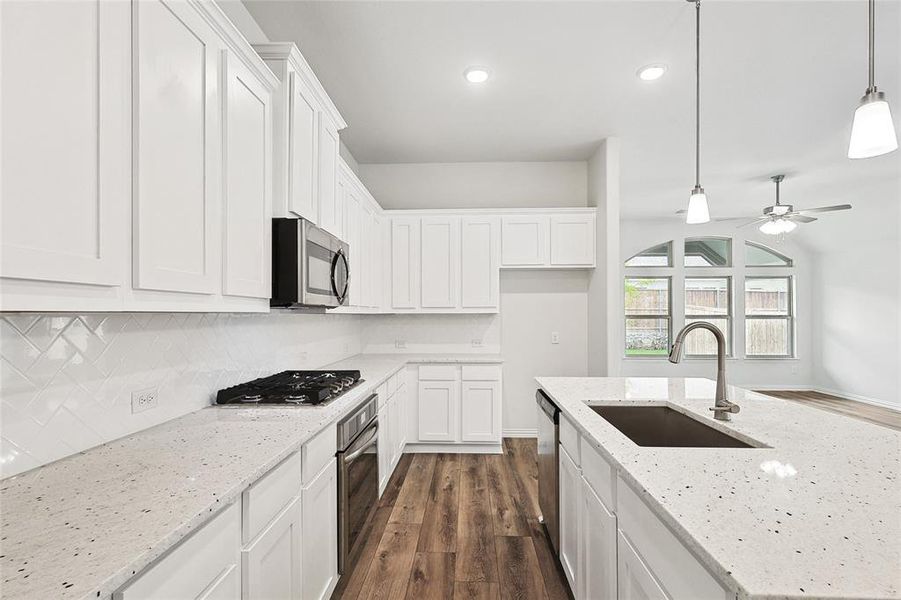 Kitchen featuring dark hardwood / wood-style flooring, ceiling fan, appliances with stainless steel finishes, pendant lighting, and sink