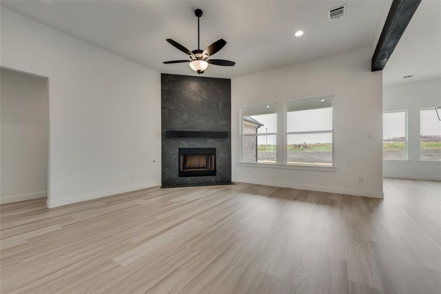 Unfurnished living room with ceiling fan, plenty of natural light, light hardwood / wood-style flooring, and a fireplace