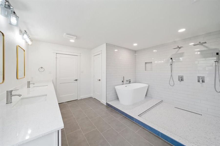 Bathroom with tiled shower, tile patterned floors, dual bowl vanity, and tile walls