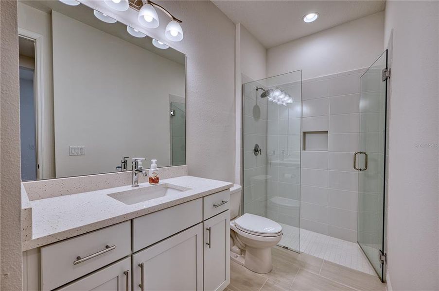 Main Hall Bath: Tile shower stall and quartz countertops.