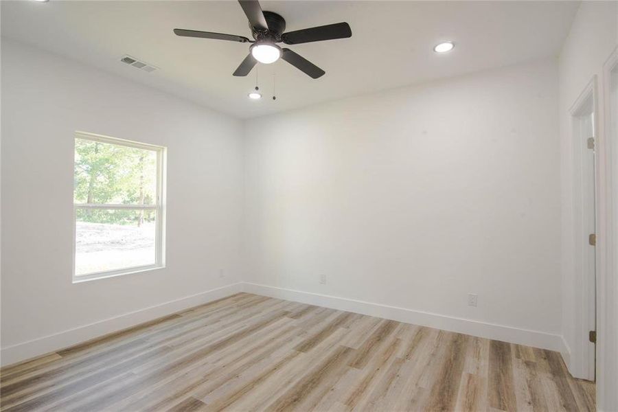 Empty room with ceiling fan and light hardwood / wood-style floors