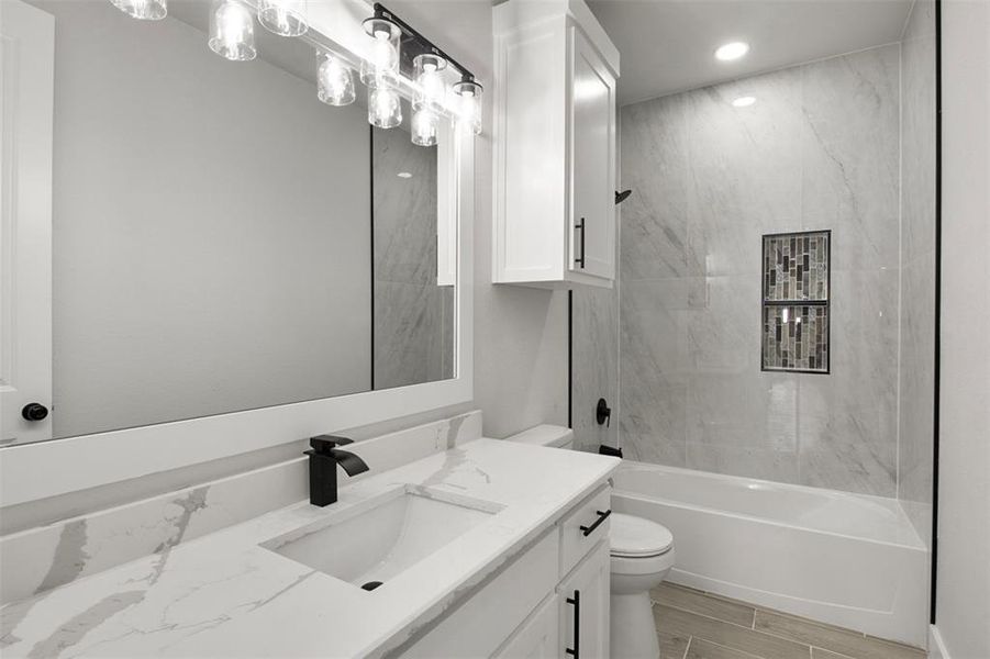 Full bathroom with tiled shower / bath, vanity, and toilet