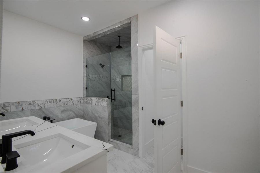 Bathroom featuring vanity, tile walls, and independent shower and bath