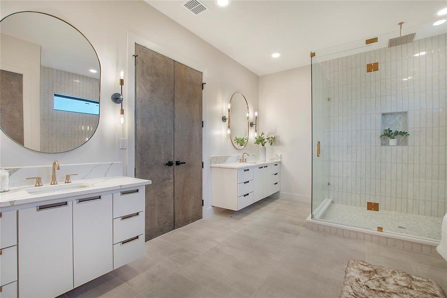 Bathroom with tile patterned flooring, a shower with shower door, and double sink vanity