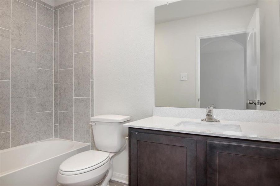 Full bathroom with tiled shower / bath combo, vanity, and toilet