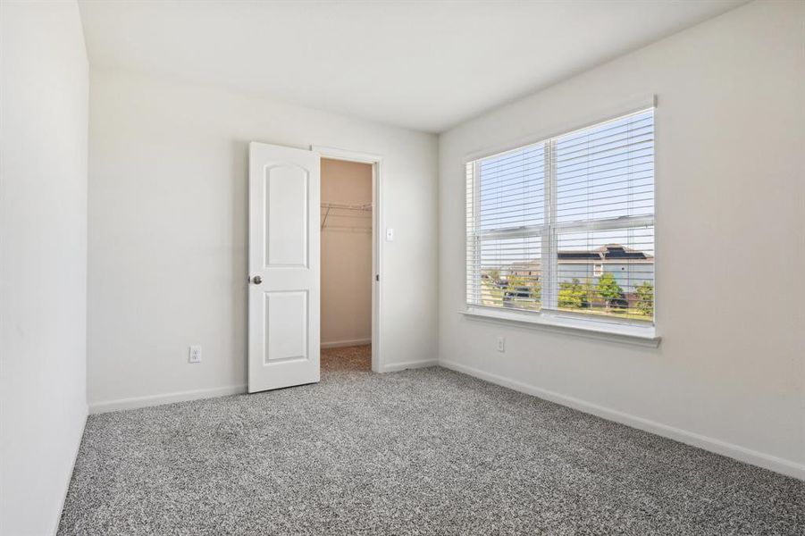 Unfurnished bedroom featuring a closet, a walk in closet, and carpet floors