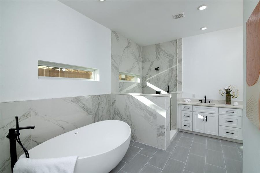 Bathroom featuring tile walls, plus walk in shower, and vanity