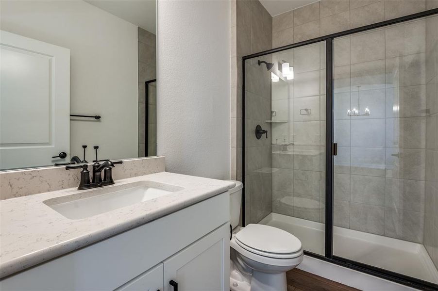 Bathroom featuring vanity, a shower with shower door, hardwood / wood-style flooring, and toilet