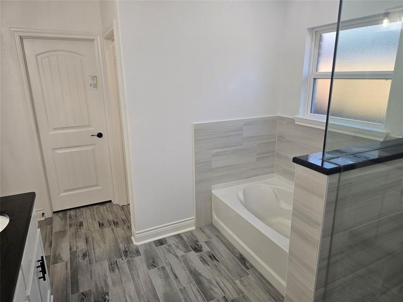 Bathroom with a tub to relax in, hardwood / wood-style floors, and vanity