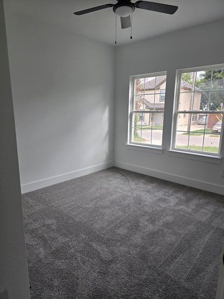 Carpeted empty room featuring ceiling fan and plenty of natural light