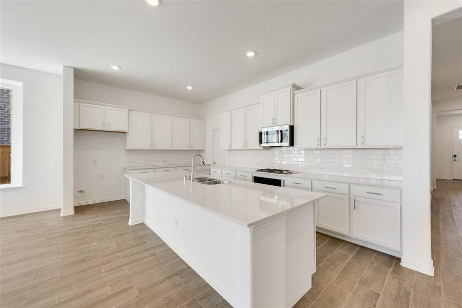 Kitchen featuring light hardwood / wood-style flooring, white cabinetry, a kitchen island with sink, and sink